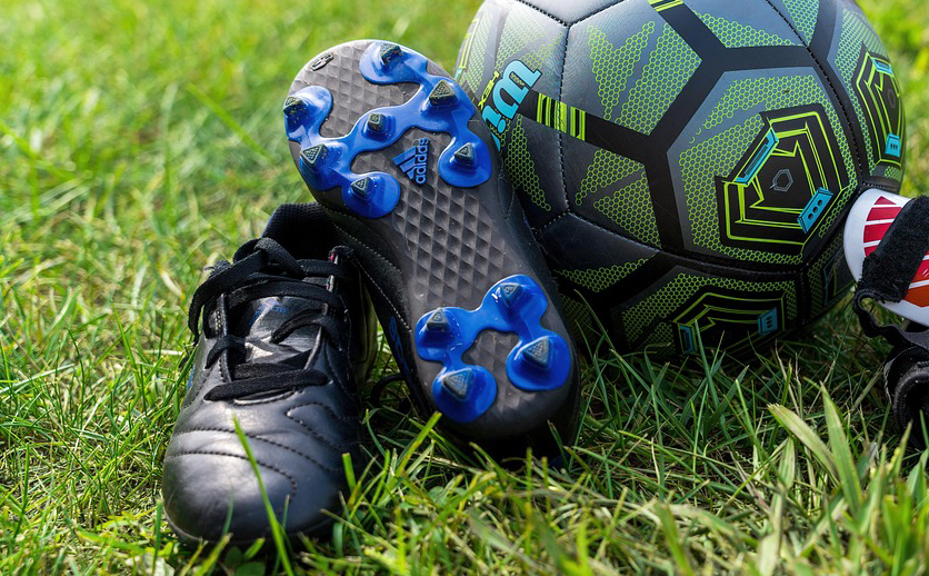 pair of blue soccer cleats that look like they are fit for a toddler sitting on the grass